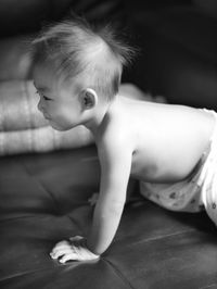 Shirtless boy crawling on bed at home