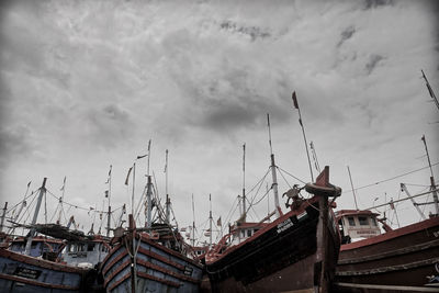 Low angle view of sailboats moored at harbor against sky