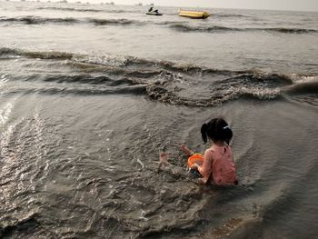 Rear view of boy sitting on beach