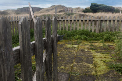 Wooden posts on landscape against sky