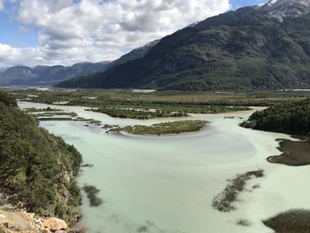 Scenic view of river by mountains against sky