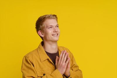 Portrait of young woman against yellow background