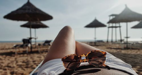 Low section of woman wearing sunglasses on beach