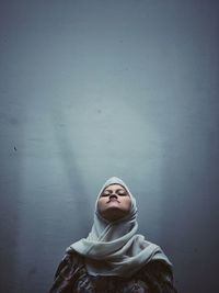 Close-up of young woman standing against wall