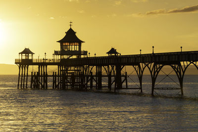 Silhouetted clevedon pier over sea against sky during sunset