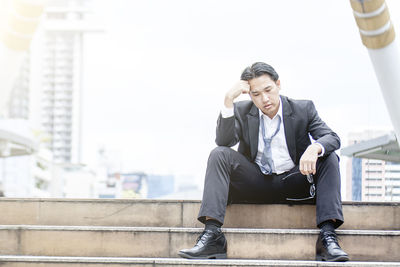 Young man sitting in front of office building