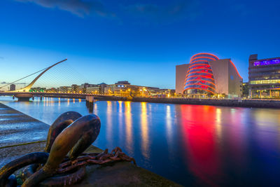 River by illuminated city against clear blue sky