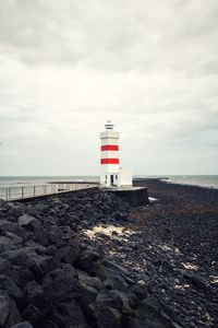 Lighthouse on beach against sky