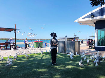 People on road against clear blue sky