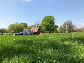 Woman relaxing on field against sky