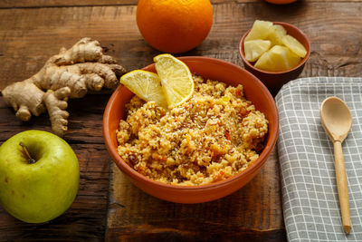 Couscous masfouf with dried fruits and nuts on a linen napkin next to a spoon and fresh fruit.