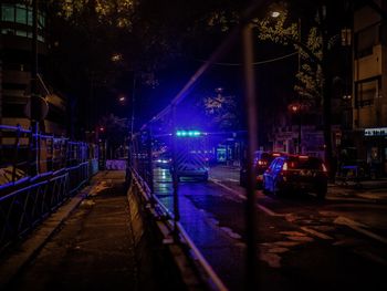 Illuminated street amidst trees in city at night