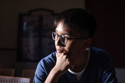 Close-up of man looking away in darkroom