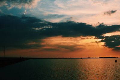 Scenic view of sea against cloudy sky during sunset