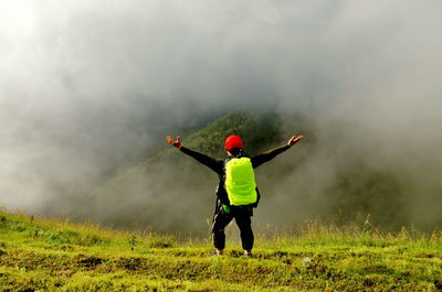 Rear view of woman in field against sky