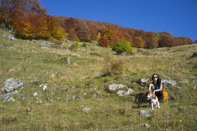 Girl with dog during a walk in the mountains stops to admire nature