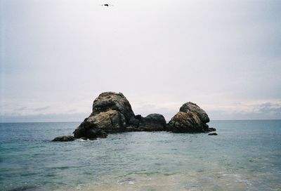 Rock formation in sea against sky