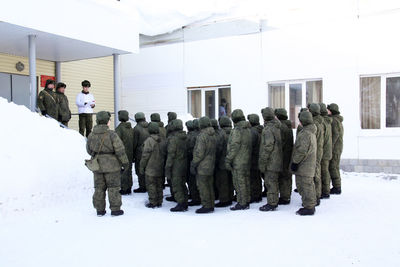 Rear view of people standing in snow