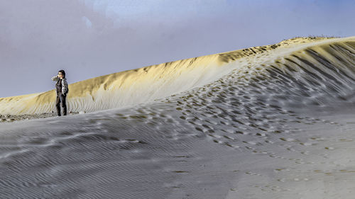 Man standing on sand against sky