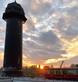 Tower amidst buildings against sky during sunset