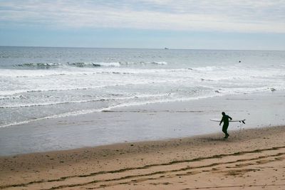 Man with paddleboard on shore at beach