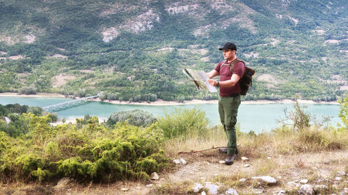 Mature man standing by lake against mountains