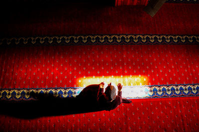 Directly above shot of sunlight falling on woman praying in mosque 