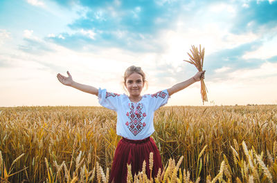 Portrait of girl holding wheat crop standing at farm