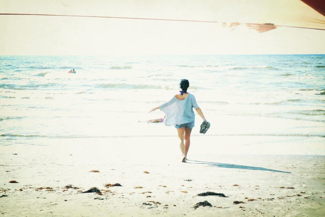 beach, sea, horizon over water, full length, sand, shore, water, lifestyles, rear view, leisure activity, sky, casual clothing, vacations, nature, tranquility, beauty in nature, scenics, tranquil scene