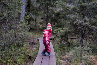 Girl smiling walking along a boardwalk in a forest in winter