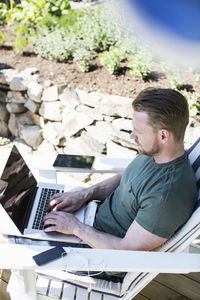 High angle view of man using laptop on lounge chair