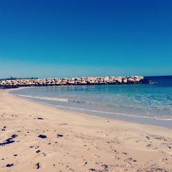 Scenic view of beach against clear blue sky