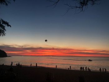 Silhouette people on beach against sky during sunset