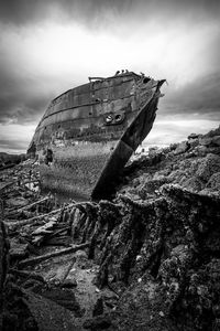 Damaged boat on beach against sky