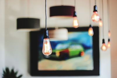 Close-up of illuminated light bulb hanging on table at home