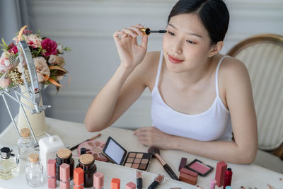 High angle view of woman apply make-up on table at home
