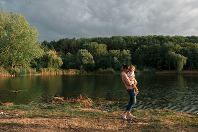 Woman standing by lake against sky