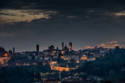 Illuminated buildings in city against sky during sunset