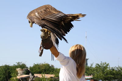 Woman flying bird against clear sky