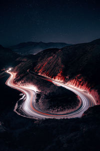 Light trails on road against sky at night