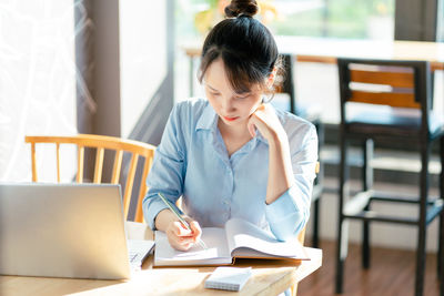 Businesswoman using laptop while sitting on table