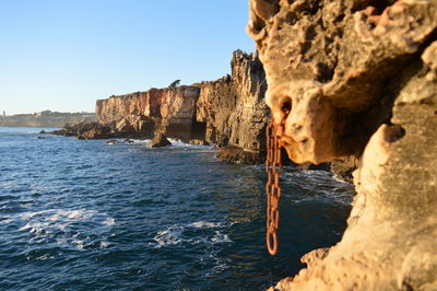 Rock formations by sea against clear sky