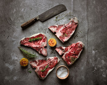 Raw steaks, butcher knife on gray background. flat layout, square image.