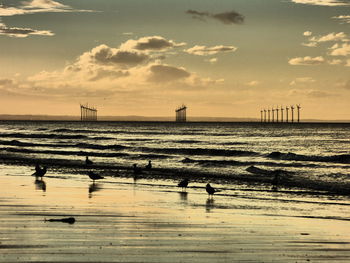 Windmills against river during sunset