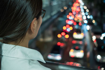 Woman looking at traffic on street at night
