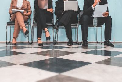 Low section of people waiting for interview on chair