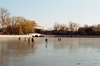 People playing in water against clear sky