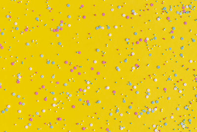 Colorful sprinkles on a yellow background