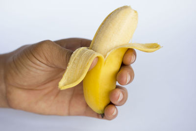 Close-up of hand holding apple against white background