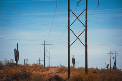 Low angle view of electricity pylon on field against sky